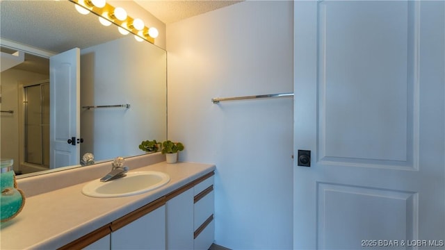 full bathroom featuring a shower with door, a textured ceiling, and vanity