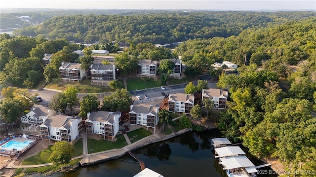 view of property location with a heavily wooded area, a nearby body of water, and nearby suburban area