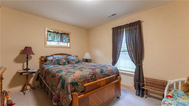 bedroom featuring baseboards, visible vents, and light colored carpet