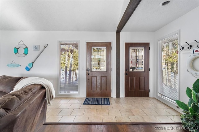 entrance foyer featuring light tile patterned floors, a textured ceiling, and a wealth of natural light