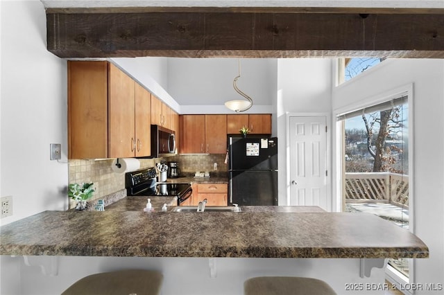 kitchen featuring a breakfast bar, decorative backsplash, brown cabinets, black appliances, and dark countertops