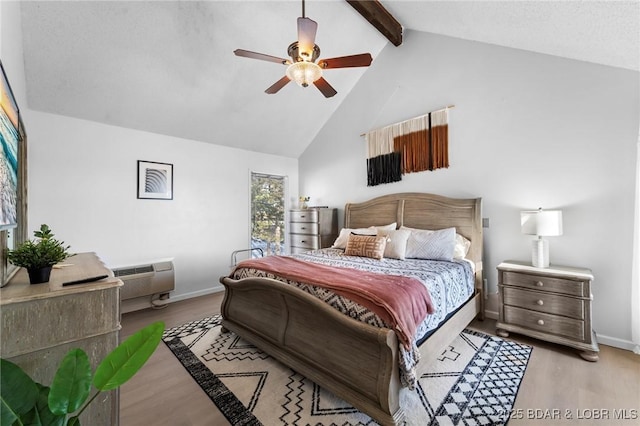 bedroom featuring high vaulted ceiling, a wall unit AC, baseboards, light wood-style floors, and beam ceiling