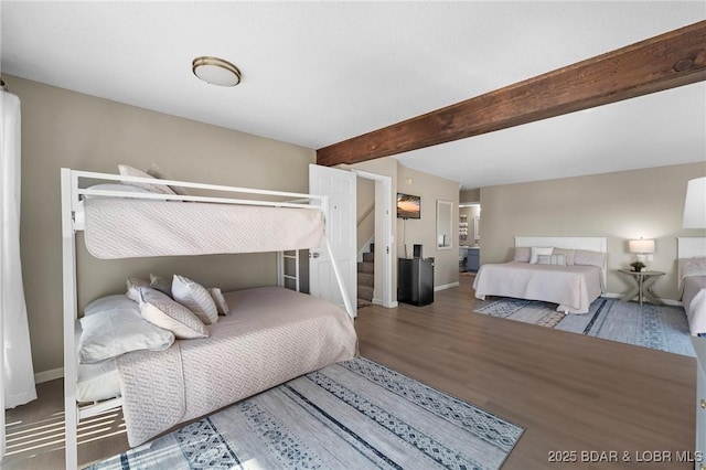 bedroom featuring beam ceiling, baseboards, and wood finished floors