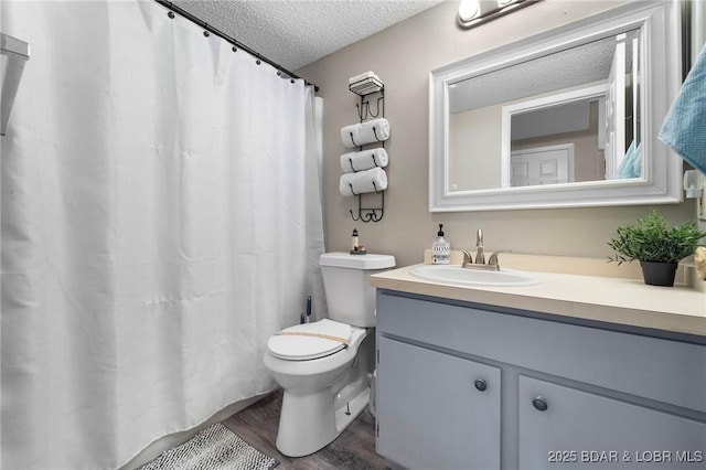 bathroom featuring a textured ceiling, toilet, wood finished floors, and vanity