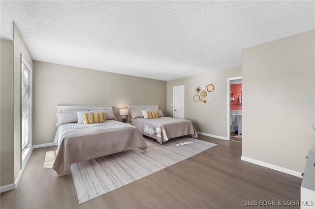 bedroom with a textured ceiling, dark wood-style flooring, and baseboards