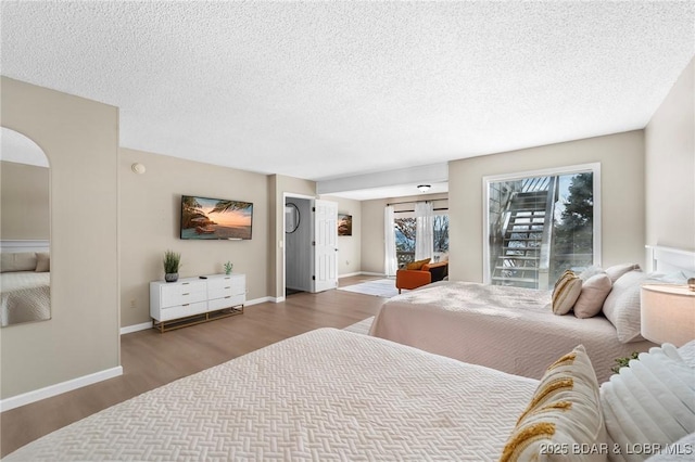 bedroom featuring arched walkways, a textured ceiling, baseboards, and wood finished floors