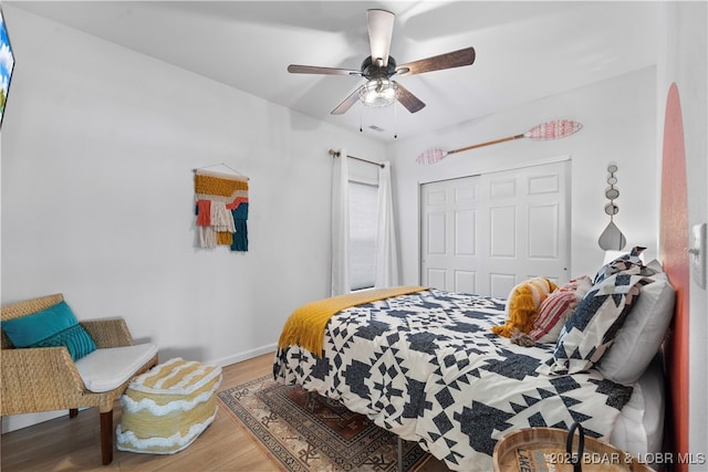 bedroom with baseboards, arched walkways, a ceiling fan, wood finished floors, and a closet