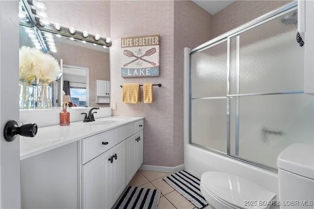 bathroom featuring enclosed tub / shower combo, toilet, vanity, baseboards, and tile patterned floors