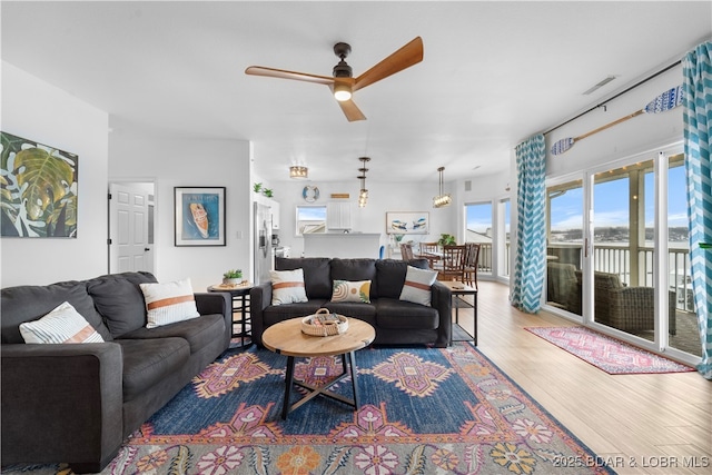 living area featuring a ceiling fan, visible vents, and wood finished floors