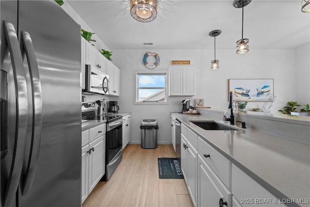 kitchen with white cabinetry, stainless steel appliances, a sink, and light countertops