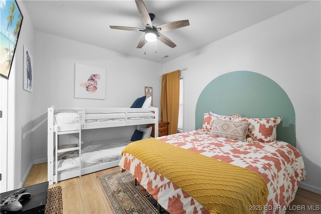 bedroom with a ceiling fan, baseboards, and wood finished floors