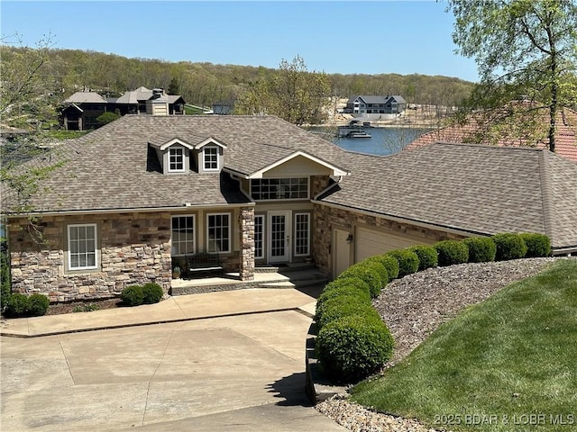 view of front of house featuring a garage, stone siding, a shingled roof, and driveway