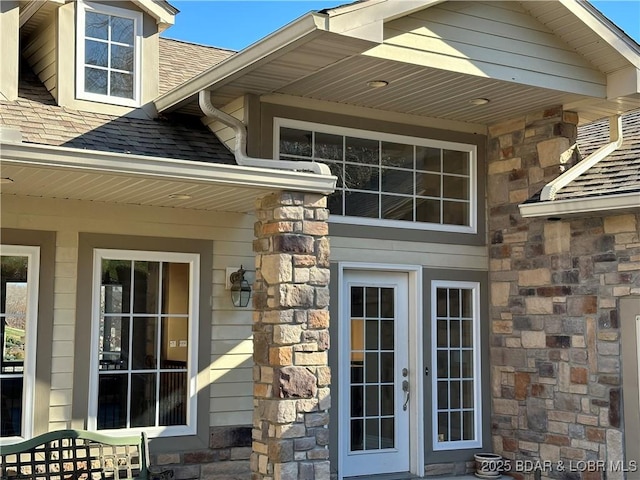 view of home's exterior with stone siding, roof with shingles, and french doors