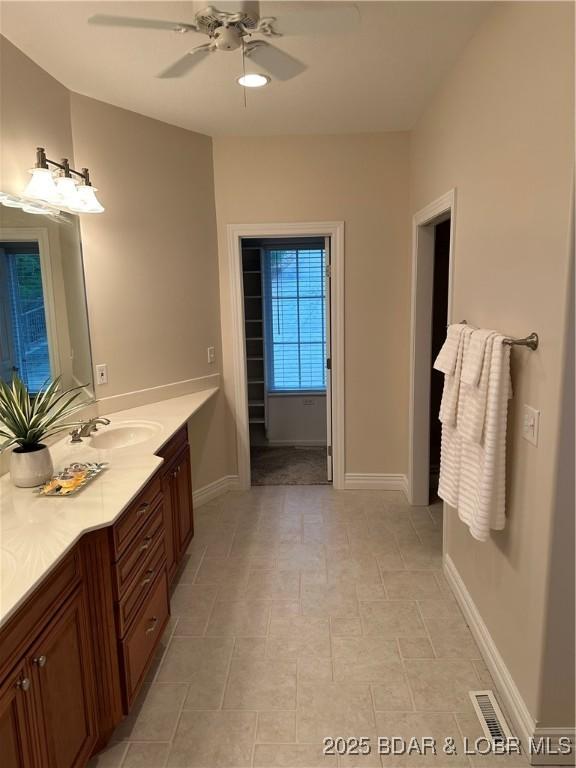 bathroom with visible vents, ceiling fan, vanity, and baseboards