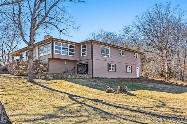 rear view of house featuring a chimney, stairway, and a yard