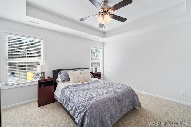 bedroom featuring light carpet, a raised ceiling, visible vents, and baseboards