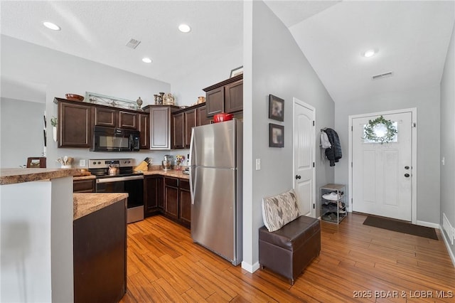 kitchen with appliances with stainless steel finishes, light wood-type flooring, vaulted ceiling, and dark brown cabinets