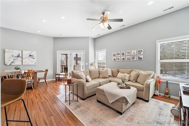 living area featuring a ceiling fan, visible vents, light wood-style flooring, and baseboards