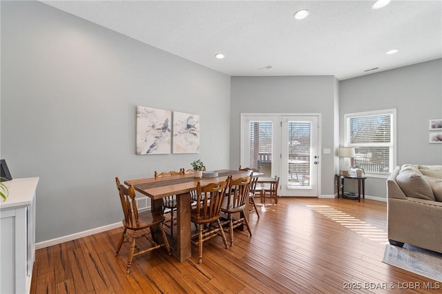 dining area with recessed lighting, a textured ceiling, baseboards, and wood finished floors