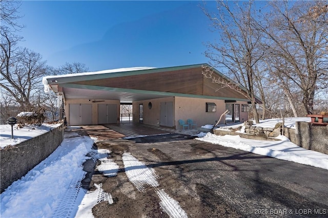 view of front of home featuring a carport, driveway, and stucco siding