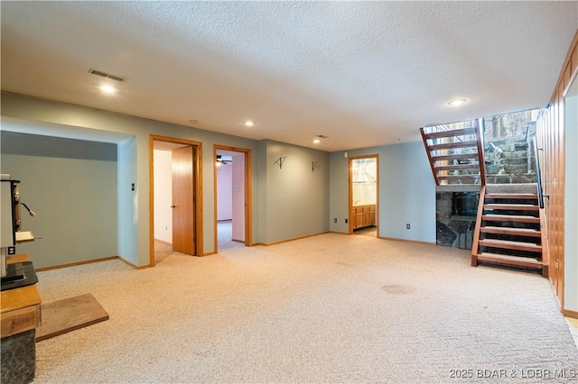 finished below grade area with a textured ceiling, recessed lighting, visible vents, baseboards, and carpet