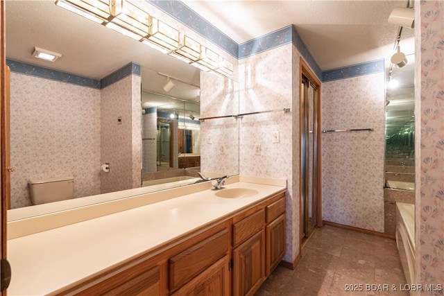 bathroom featuring toilet, vanity, baseboards, a tub, and wallpapered walls