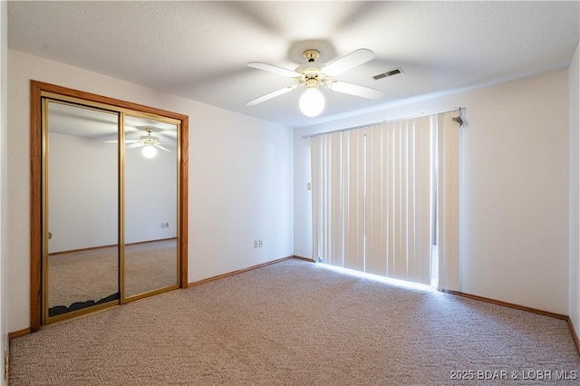 unfurnished bedroom with carpet floors, a closet, visible vents, a ceiling fan, and baseboards