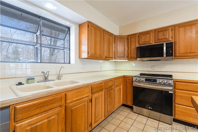 kitchen with decorative backsplash, appliances with stainless steel finishes, light countertops, and a sink