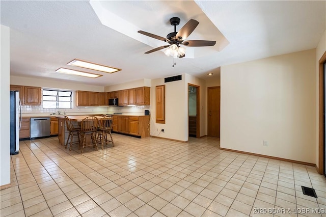 kitchen featuring stainless steel appliances, light countertops, a breakfast bar area, and light tile patterned floors