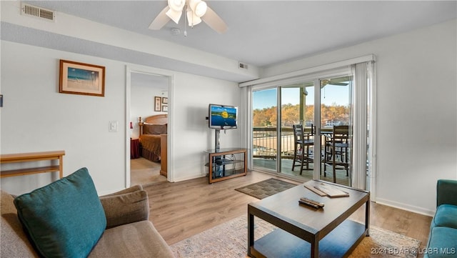 living room featuring light wood-style floors, visible vents, and baseboards