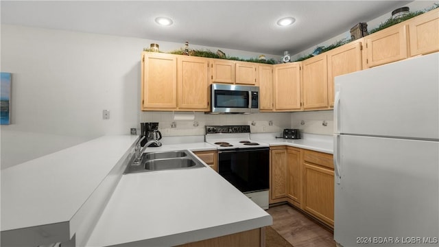 kitchen featuring light brown cabinets, white appliances, a sink, light countertops, and backsplash