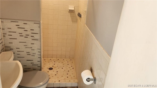 full bath with a stall shower, tile walls, and toilet