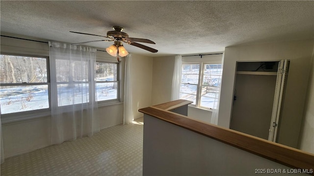 corridor featuring a textured ceiling, an upstairs landing, and light colored carpet