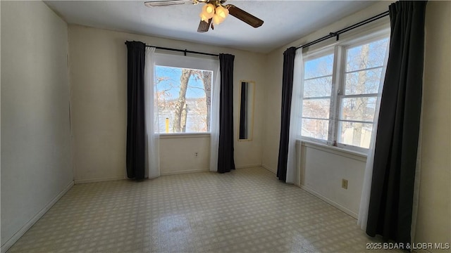 unfurnished room featuring a wealth of natural light, ceiling fan, and baseboards