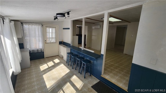 interior space with blue cabinetry, a kitchen bar, light floors, and a textured ceiling