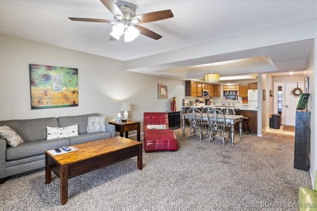 living room featuring a ceiling fan, a tray ceiling, and light carpet