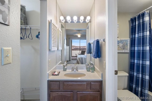 bathroom featuring vanity, a textured wall, toilet, ensuite bathroom, and ceiling fan