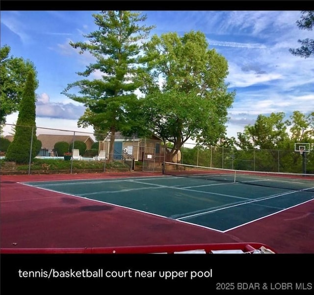 view of tennis court featuring community basketball court and fence