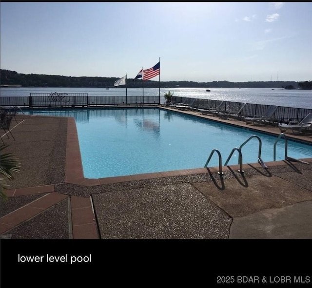 community pool featuring a water view and fence