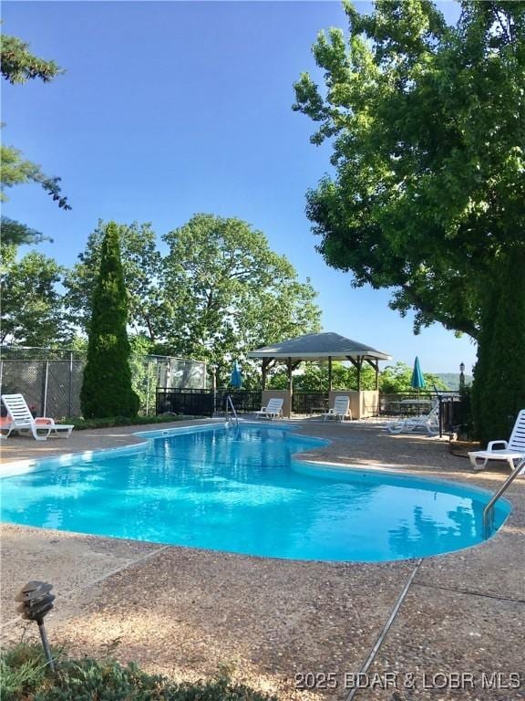 pool with a patio area and fence