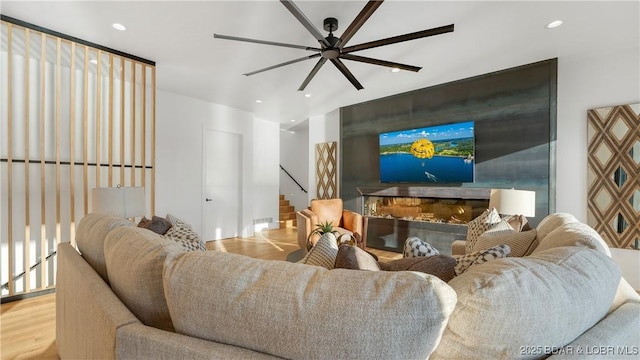 living area featuring ceiling fan, light wood finished floors, a premium fireplace, and recessed lighting