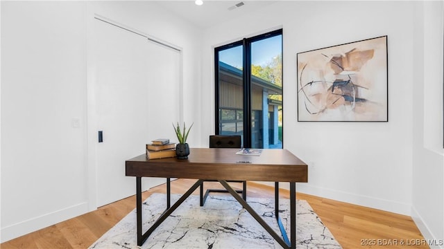 office space featuring wood finished floors, visible vents, and baseboards