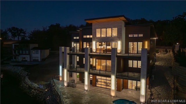 back of house at twilight with a patio and a balcony