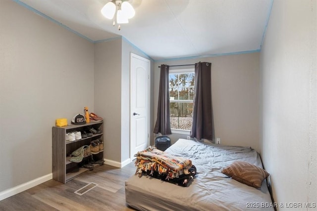 bedroom with a ceiling fan, wood finished floors, visible vents, and baseboards