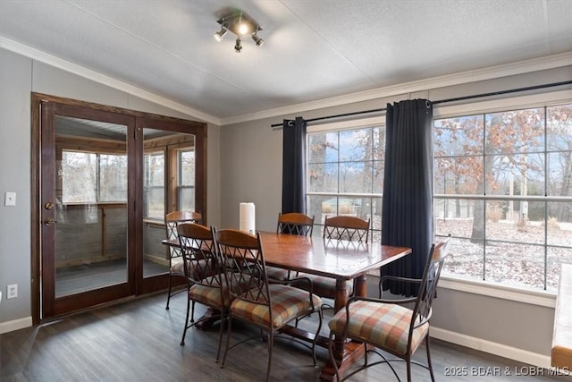 dining room with crown molding, vaulted ceiling, dark wood finished floors, and baseboards