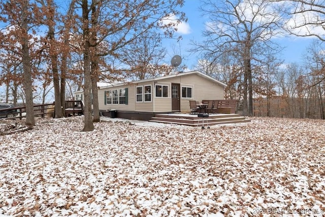 snow covered back of property featuring fence and a wooden deck