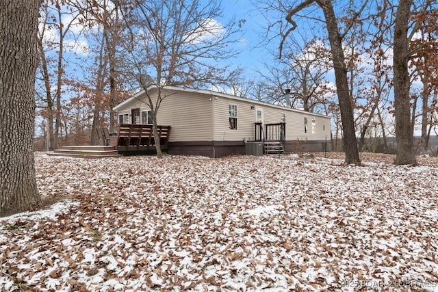 snow covered rear of property with a wooden deck