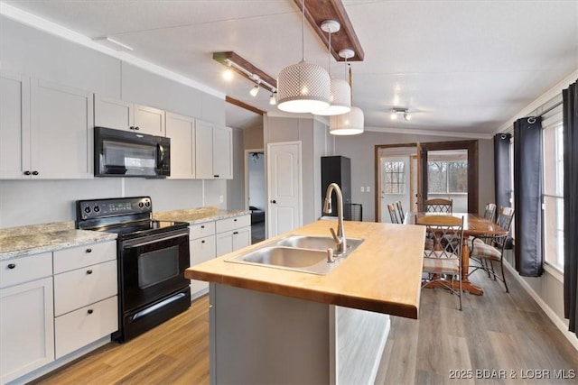 kitchen with decorative light fixtures, white cabinetry, a sink, an island with sink, and black appliances