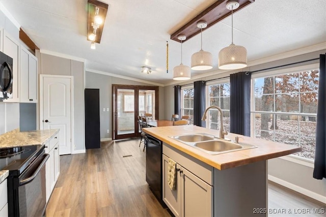 kitchen with decorative light fixtures, a sink, white cabinetry, black appliances, and a center island with sink