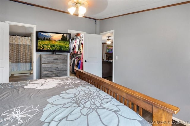 bedroom with ensuite bathroom, a closet, a walk in closet, and crown molding